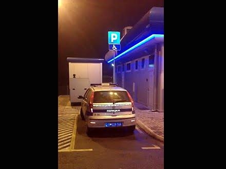 Parkirano policijsko vozilo na mestu za invalide.